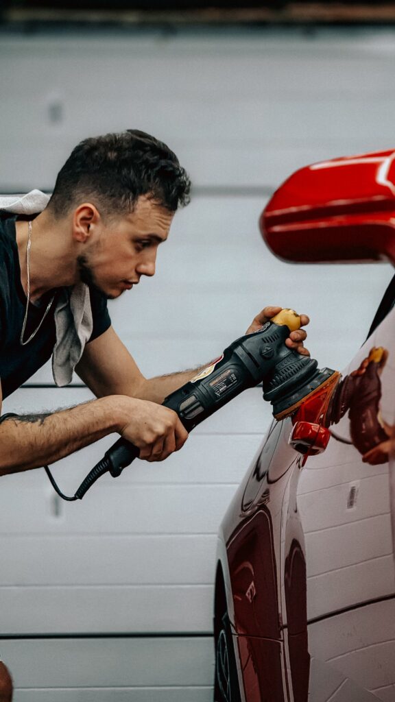 Detailer polishing a red car to a mirror finish Detailer polishing a red car to a mirror finish