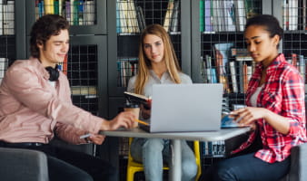 three-happy-students-writing-notebooks-laptop-library